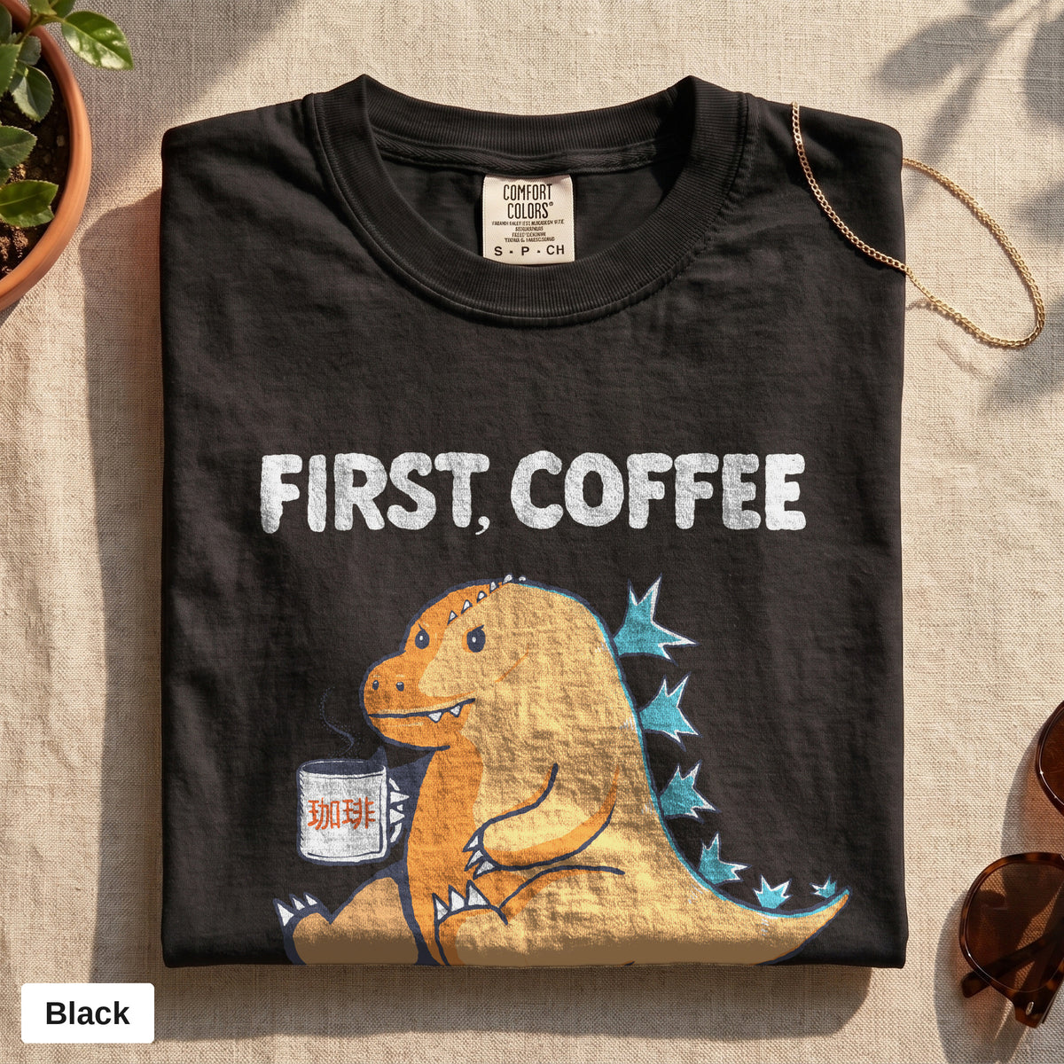 First Coffee dinosaur graphic tee, Comfort Colors 1717 in Black, folded flat lay