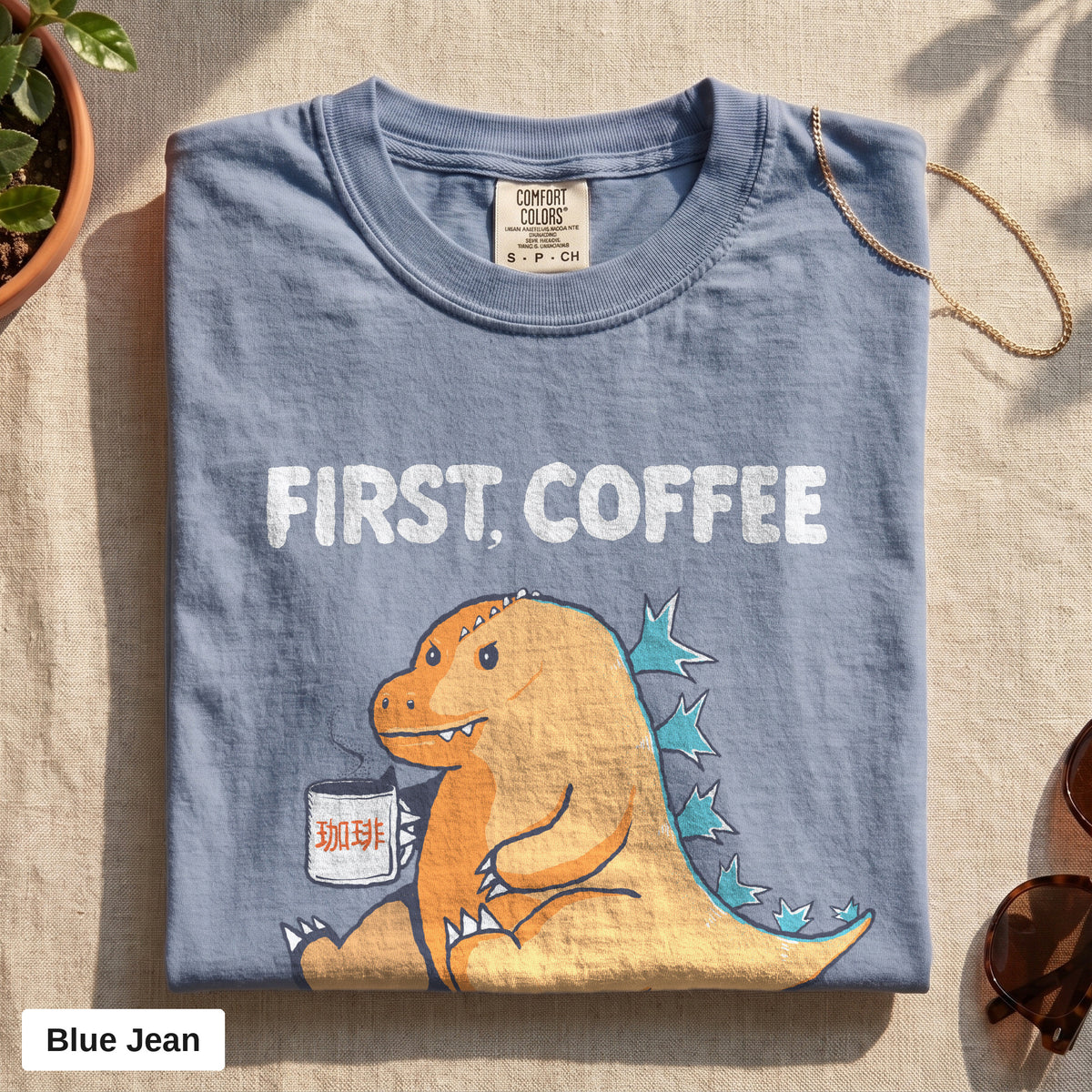 First Coffee dinosaur graphic tee, Comfort Colors 1717 in Blue Jean, folded flat lay