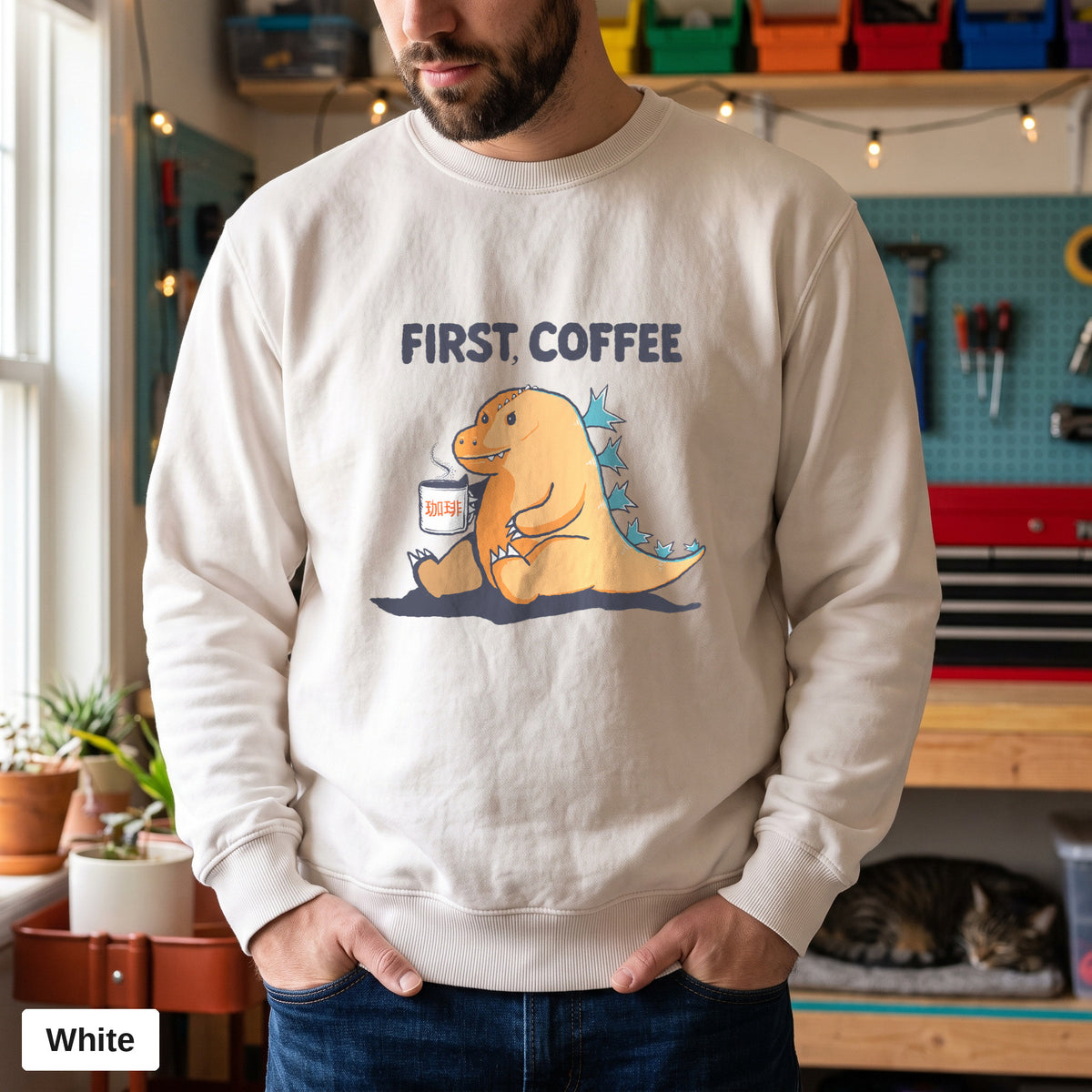 White Comfort Colors crewneck sweatshirt worn by a man, First Coffee kaiju design printed on the chest