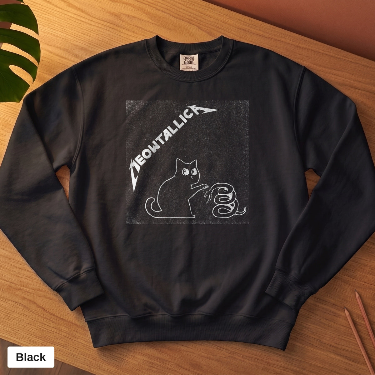 Black Comfort Colors crewneck sweatshirt, folded flat lay, metal cat and snake design printed on the chest