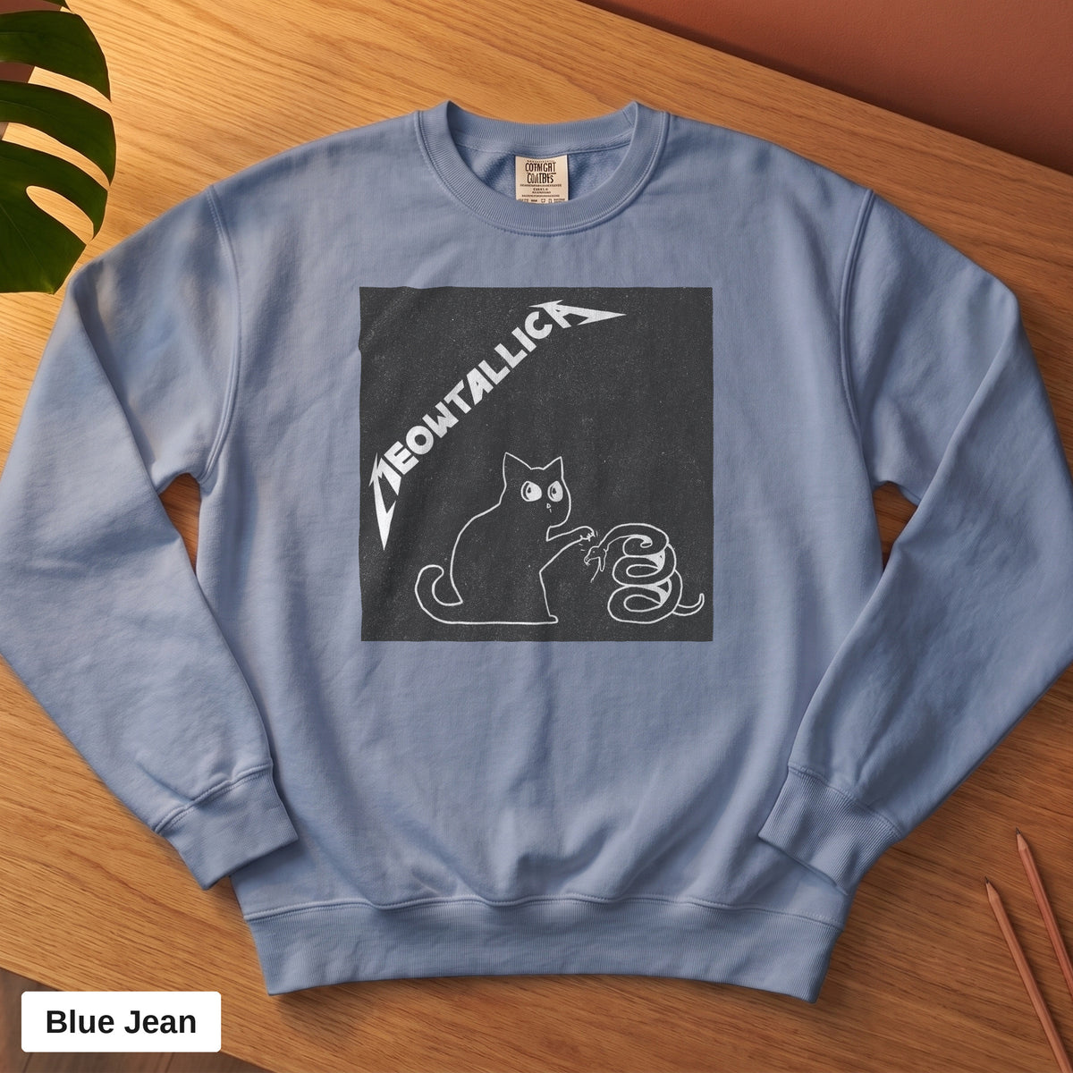 Blue Jean Comfort Colors crewneck sweatshirt, folded flat lay, metal cat and snake design printed on the chest