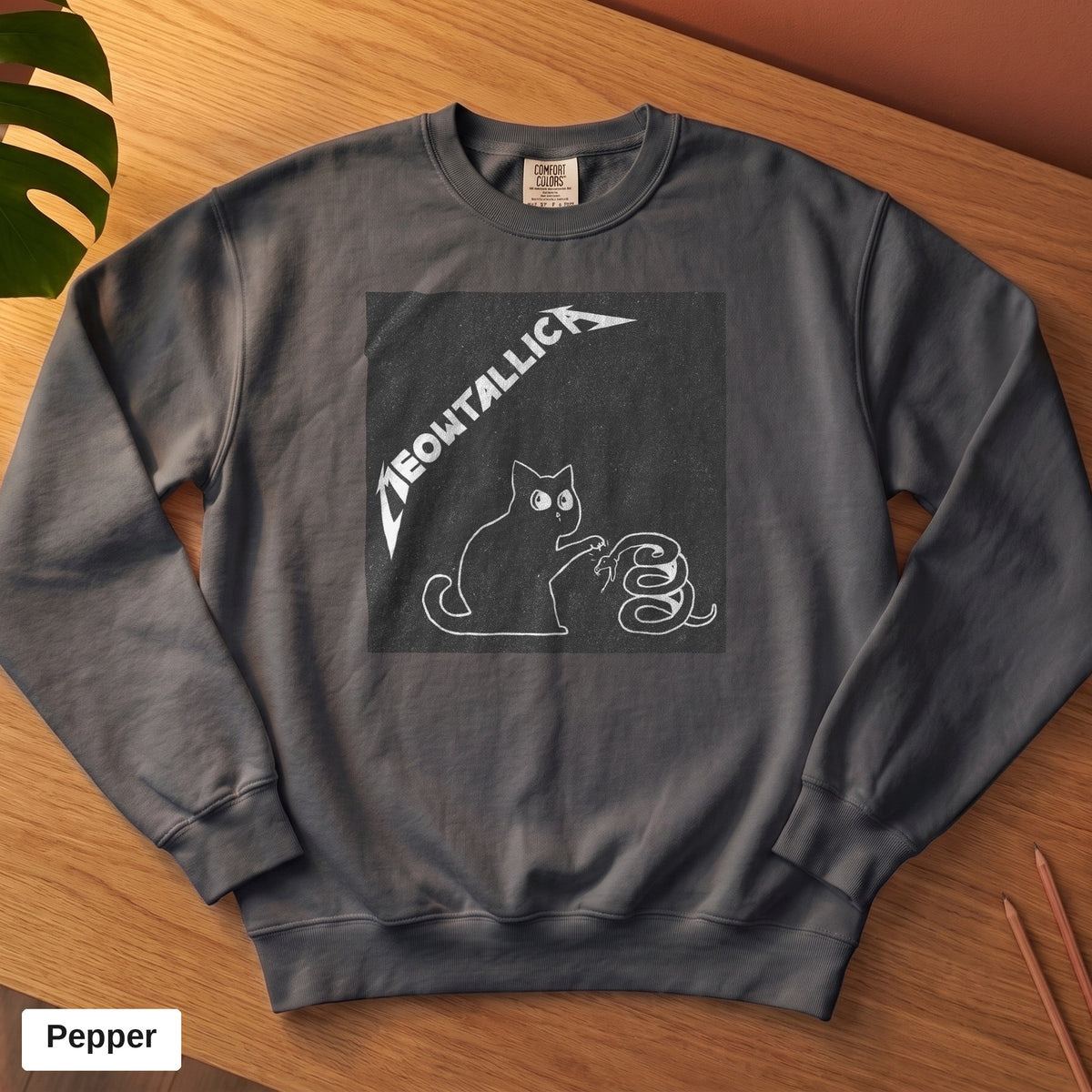 Pepper Comfort Colors crewneck sweatshirt, folded flat lay, metal cat and snake design printed on the chest