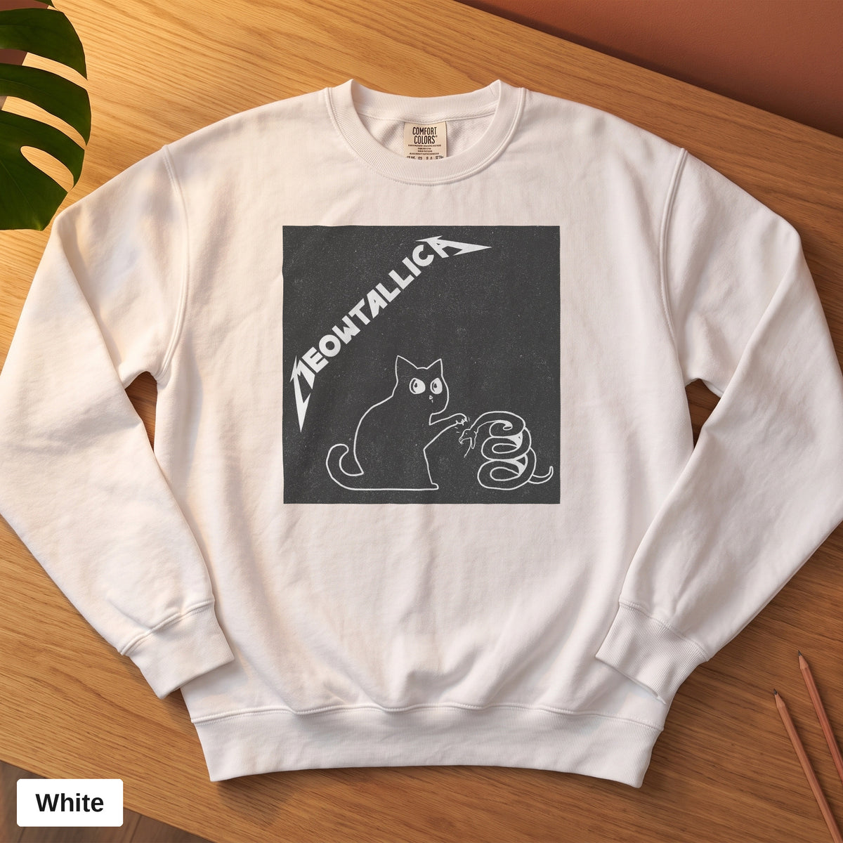 White Comfort Colors crewneck sweatshirt, folded flat lay, metal cat and snake design printed on the chest