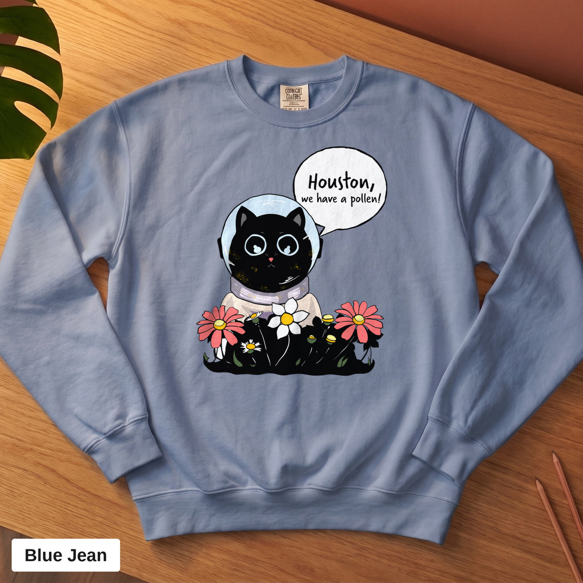 Blue Jean Comfort Colors crewneck sweatshirt, folded flat lay, Houston We Have A Pollen cat astronaut design printed on the chest
