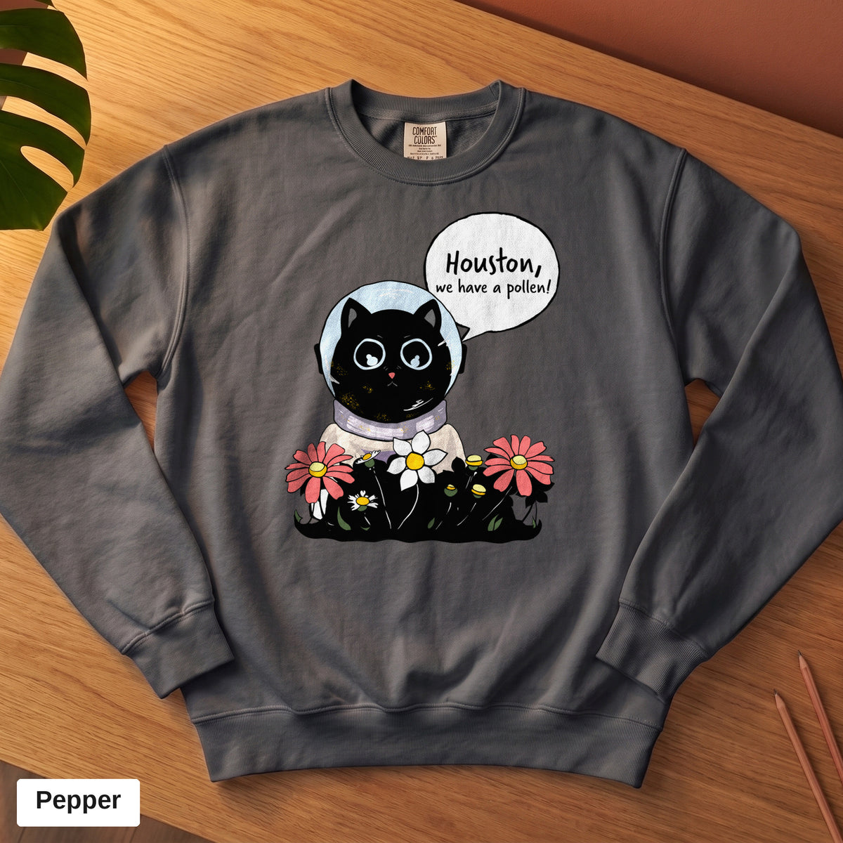 Pepper Comfort Colors crewneck sweatshirt, folded flat lay, Houston We Have A Pollen cat astronaut design printed on the chest