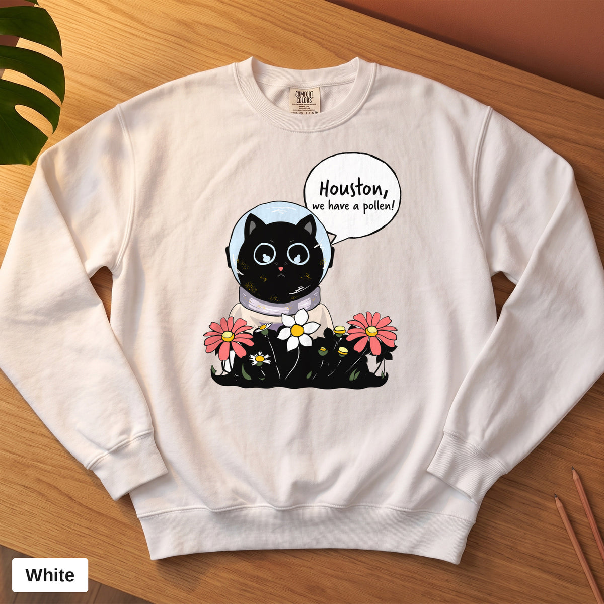 White Comfort Colors crewneck sweatshirt, folded flat lay, Houston We Have A Pollen cat astronaut design printed on the chest