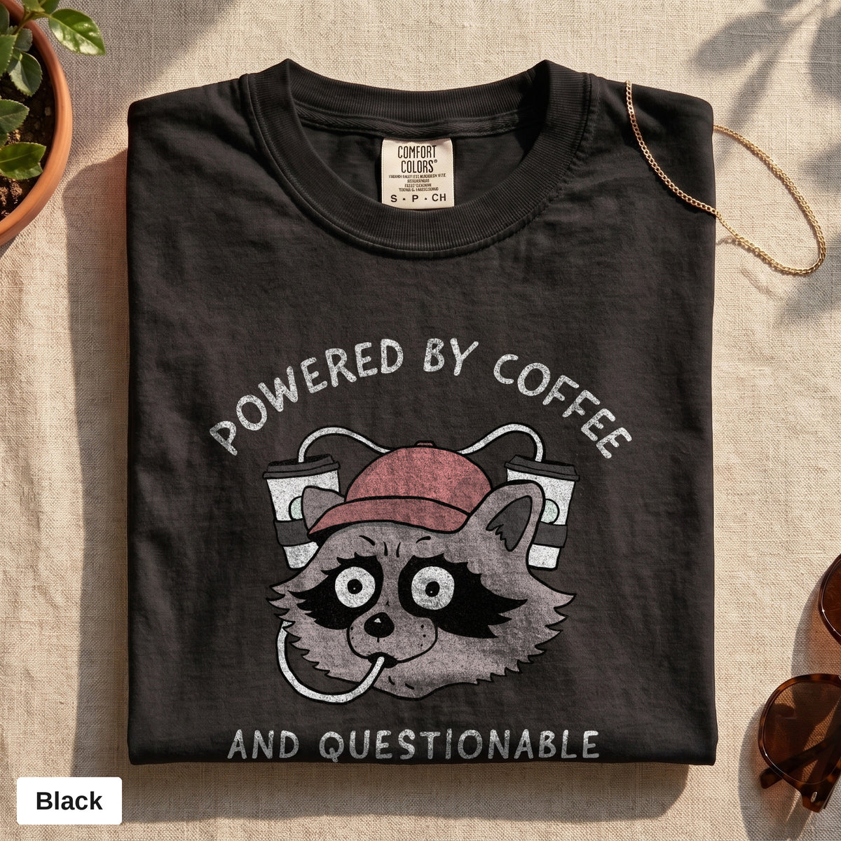 Powered By Coffee And Questionable Life Choices raccoon tee, Comfort Colors 1717 in Black, folded flat lay