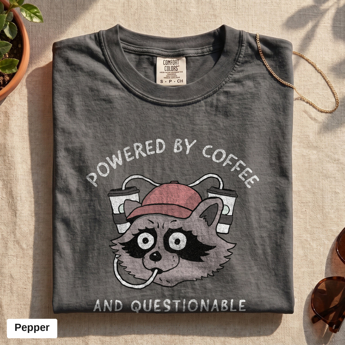 Powered By Coffee And Questionable Life Choices raccoon tee, Comfort Colors 1717 in Pepper, folded flat lay
