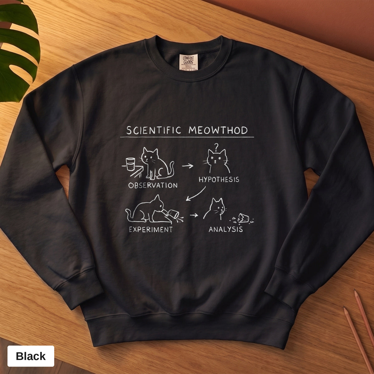 Black Comfort Colors crewneck sweatshirt, folded flat lay, Scientific Meowthod cat science diagram printed on the chest