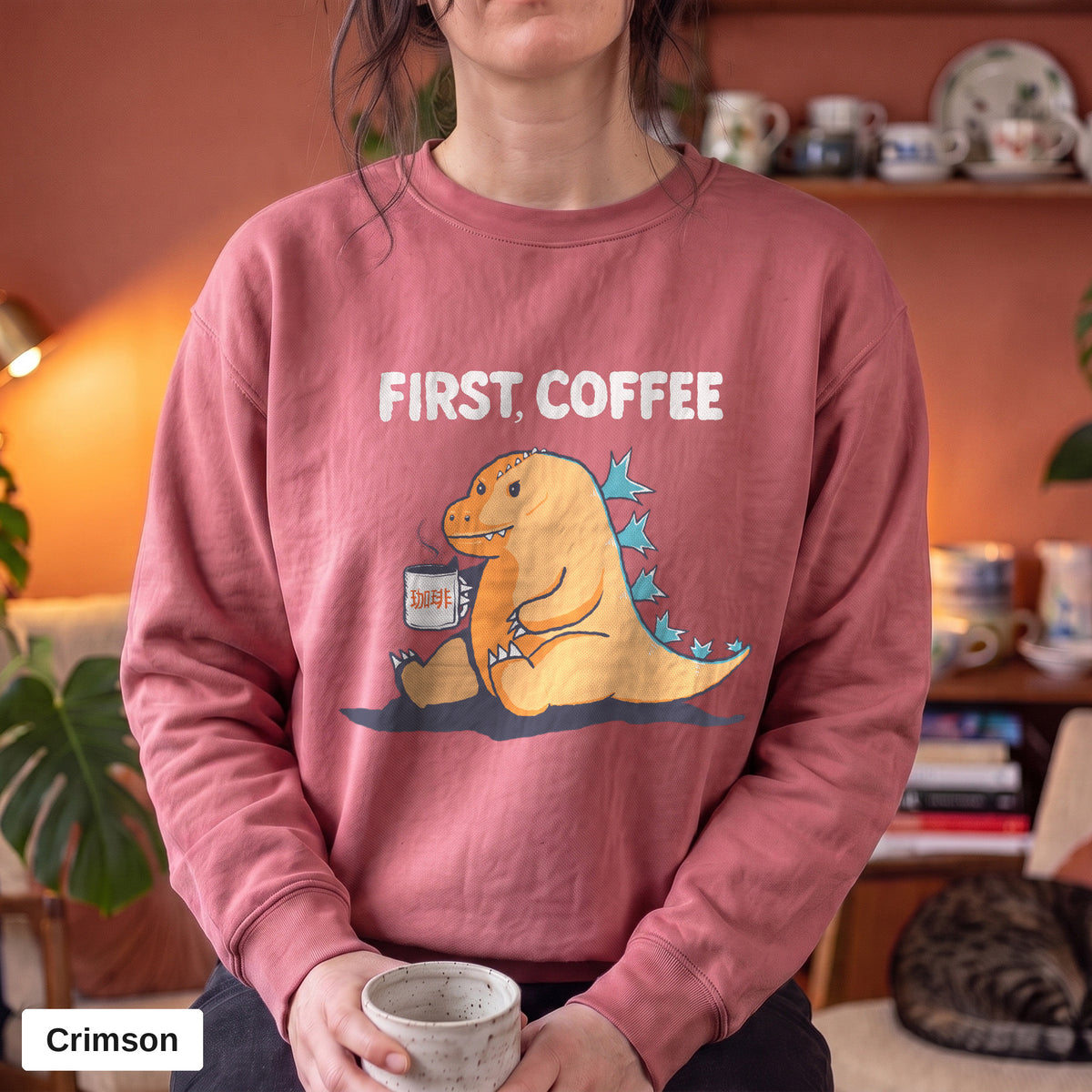 Crimson Comfort Colors crewneck sweatshirt worn by a model, First Coffee kaiju design printed on the chest